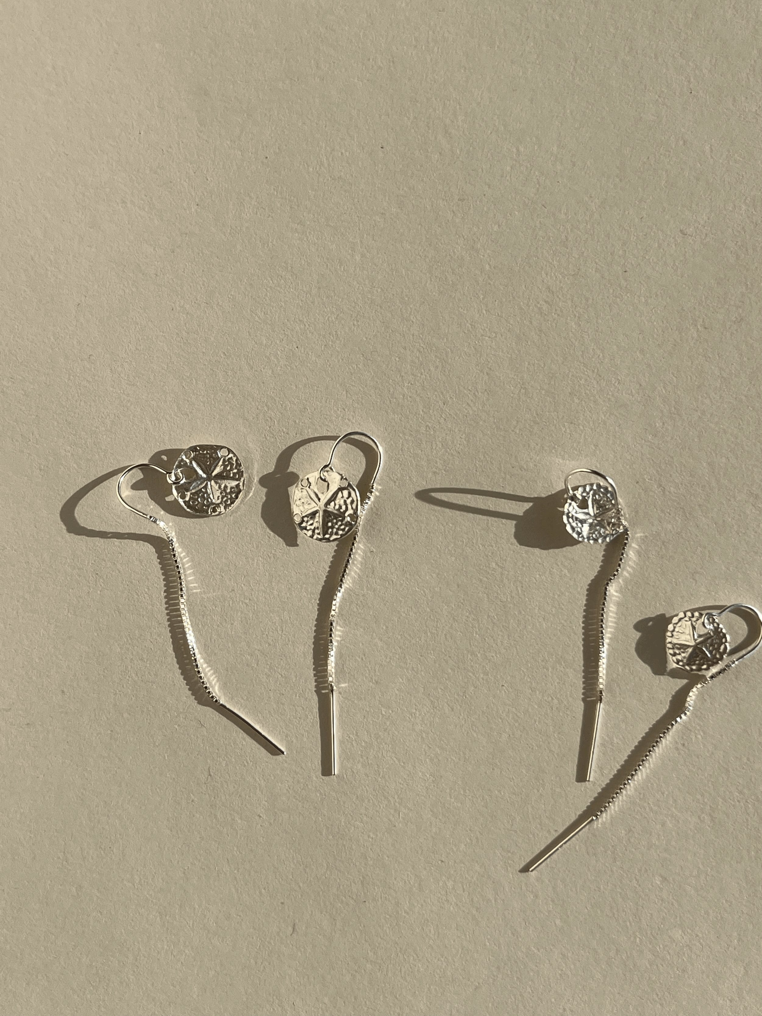  Two pairs of sterling silver sand dollar threader earrings—one 12mm pair and one 10mm pair—displayed on a neutral background