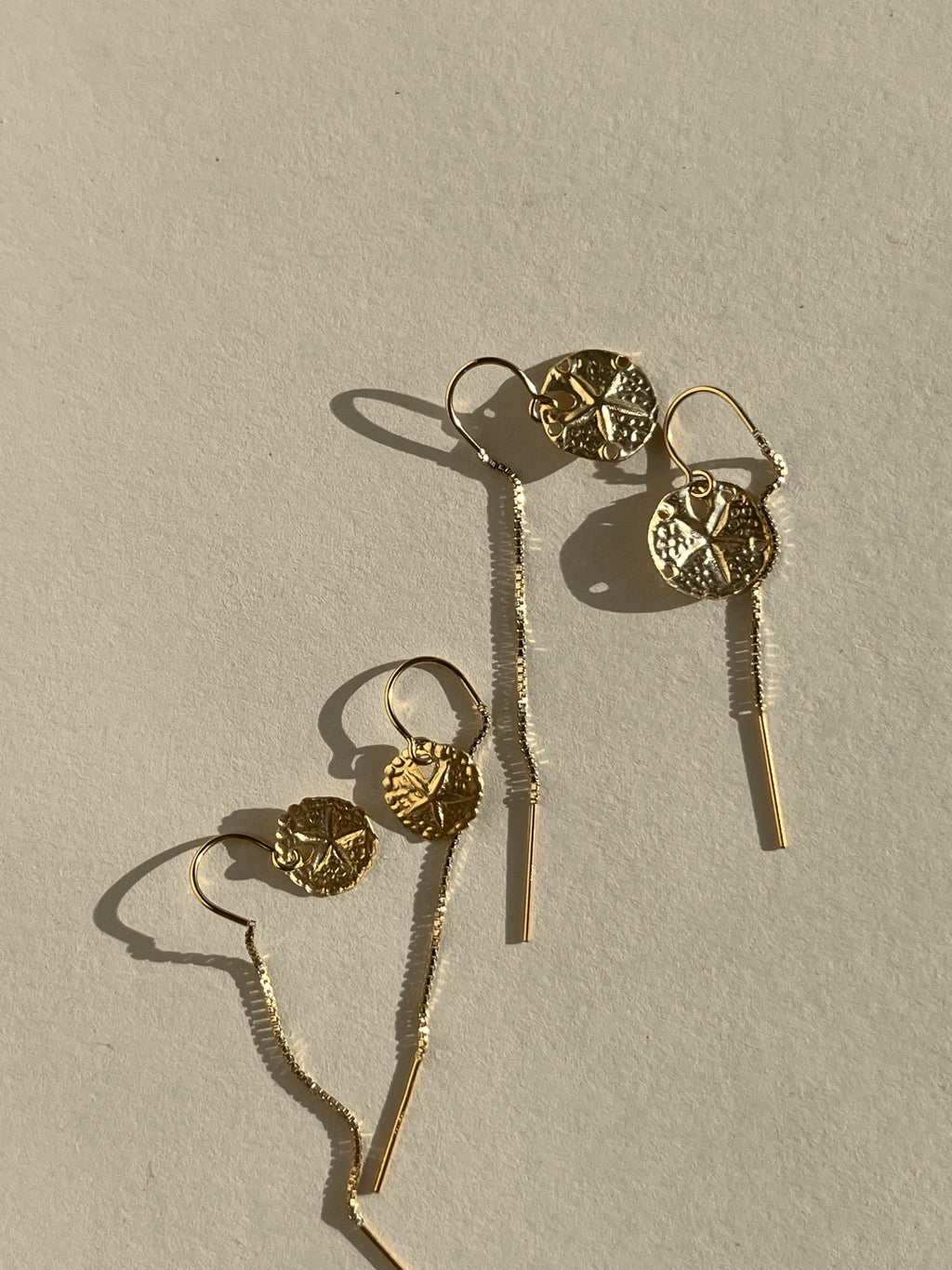 Two pairs of yellow gold-filled sand dollar threader earrings—one 12mm pair and one 10mm pair—displayed on a neutral background