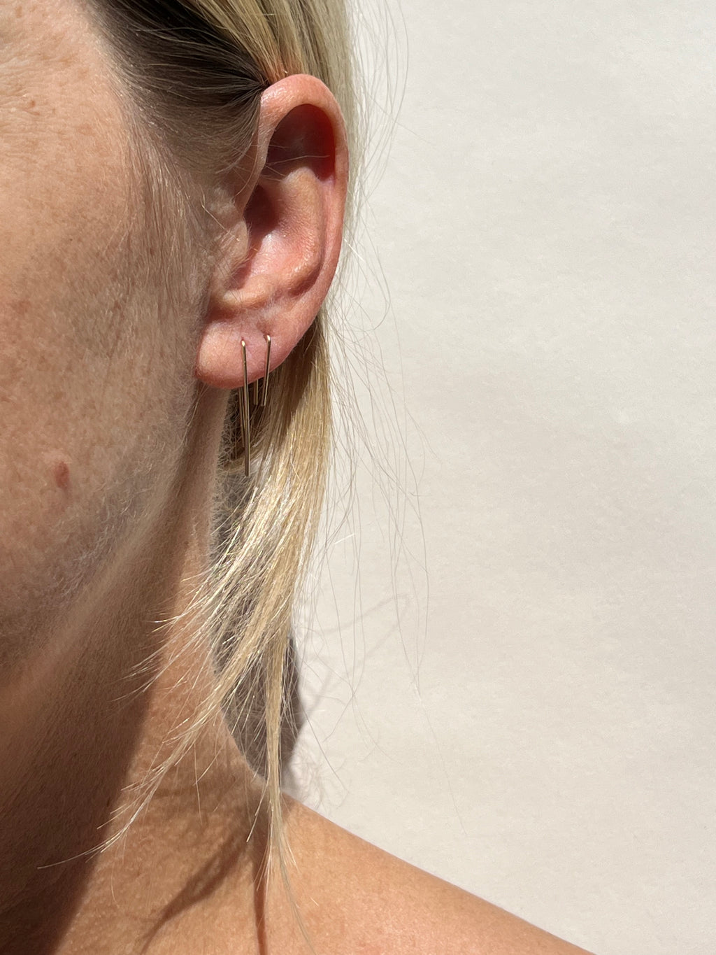 Model wearing the Long Petite Staple Earring in her first ear piercing and the Short Petite Staple Earring in her second ear piercing, both in yellow gold-filled