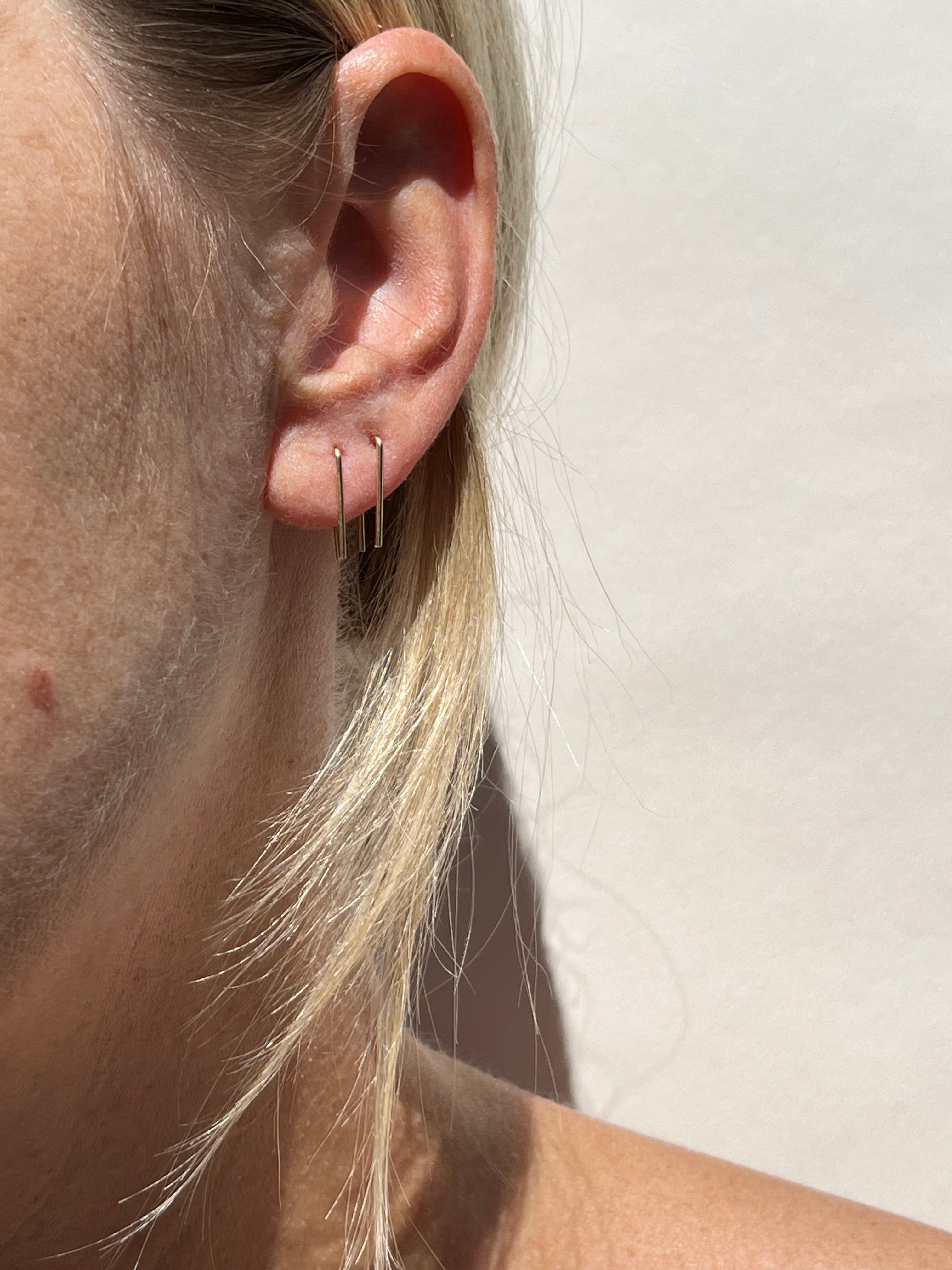 Model wearing yellow gold-filled Short Petite Staple Earrings in her first and second ear piercings.