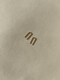 Close-up of yellow gold-filled Staple Earrings on a neutral backdrop, showing their sleek, polished finish
