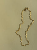 Thalken's small link paperclip necklace in yellow gold-filled on neutral backdrop in warm light