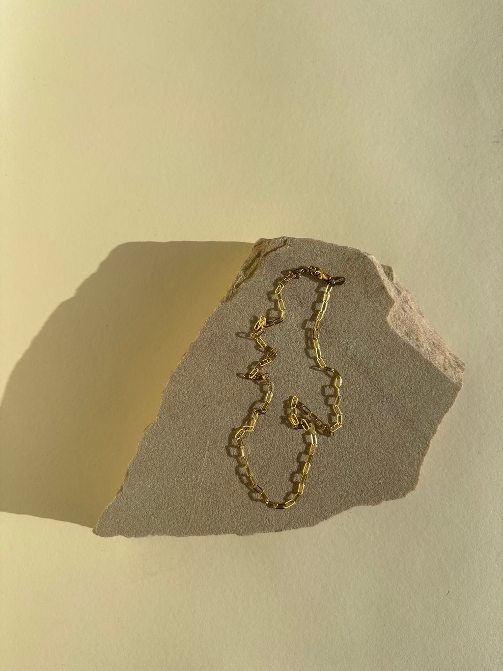 Thalken's small link paperclip necklace in yellow gold-filled on a rock in warm light