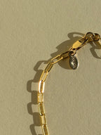 Close-up of metal THALKEN tag detail of Thalken's small link paperclip necklace