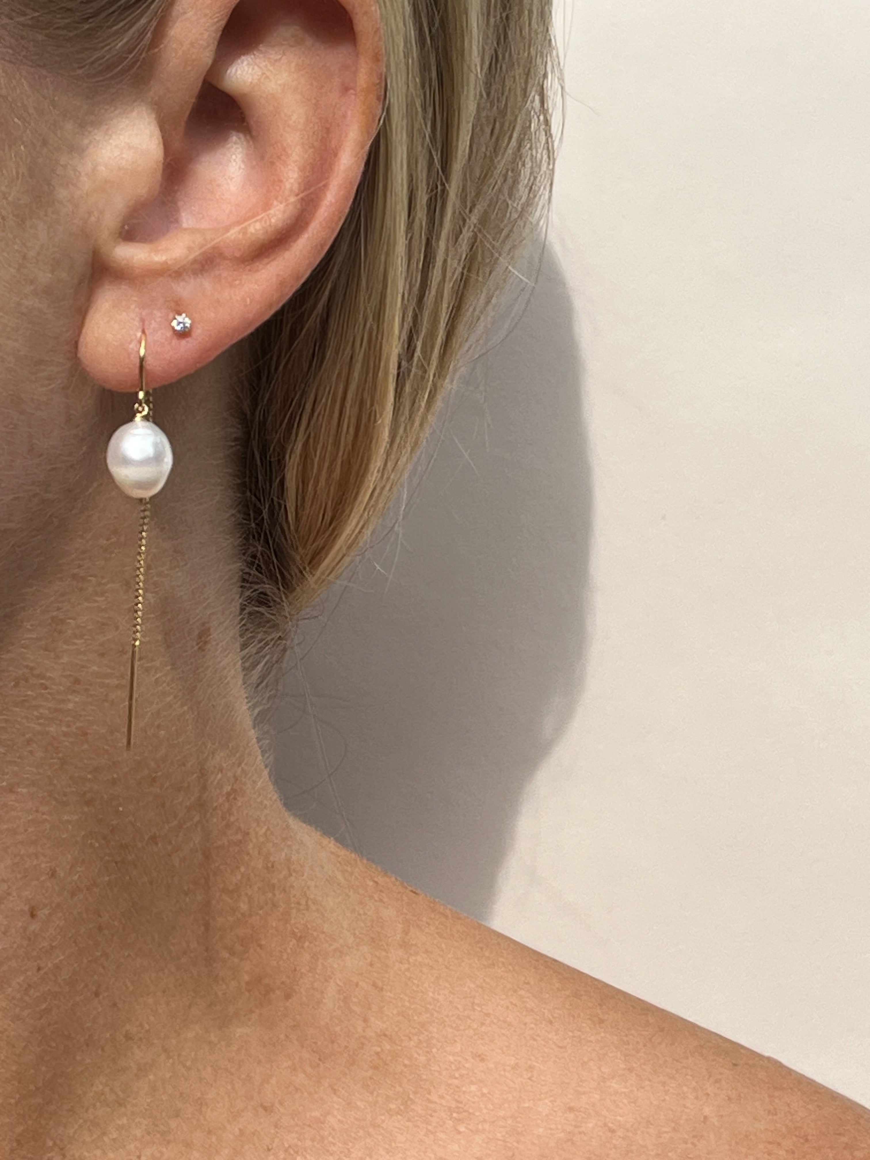 Model wearing Small Freshwater Pearl Drop Earrings in yellow gold-filled in her first piercing, with Itty Bitty Crystal Studs in her second