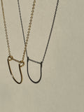 Yellow gold-filled U-shaped pendant necklace suspended in the air, close-up view.