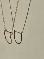 Yellow gold-filled U-shaped pendant necklace suspended in the air, close-up view.