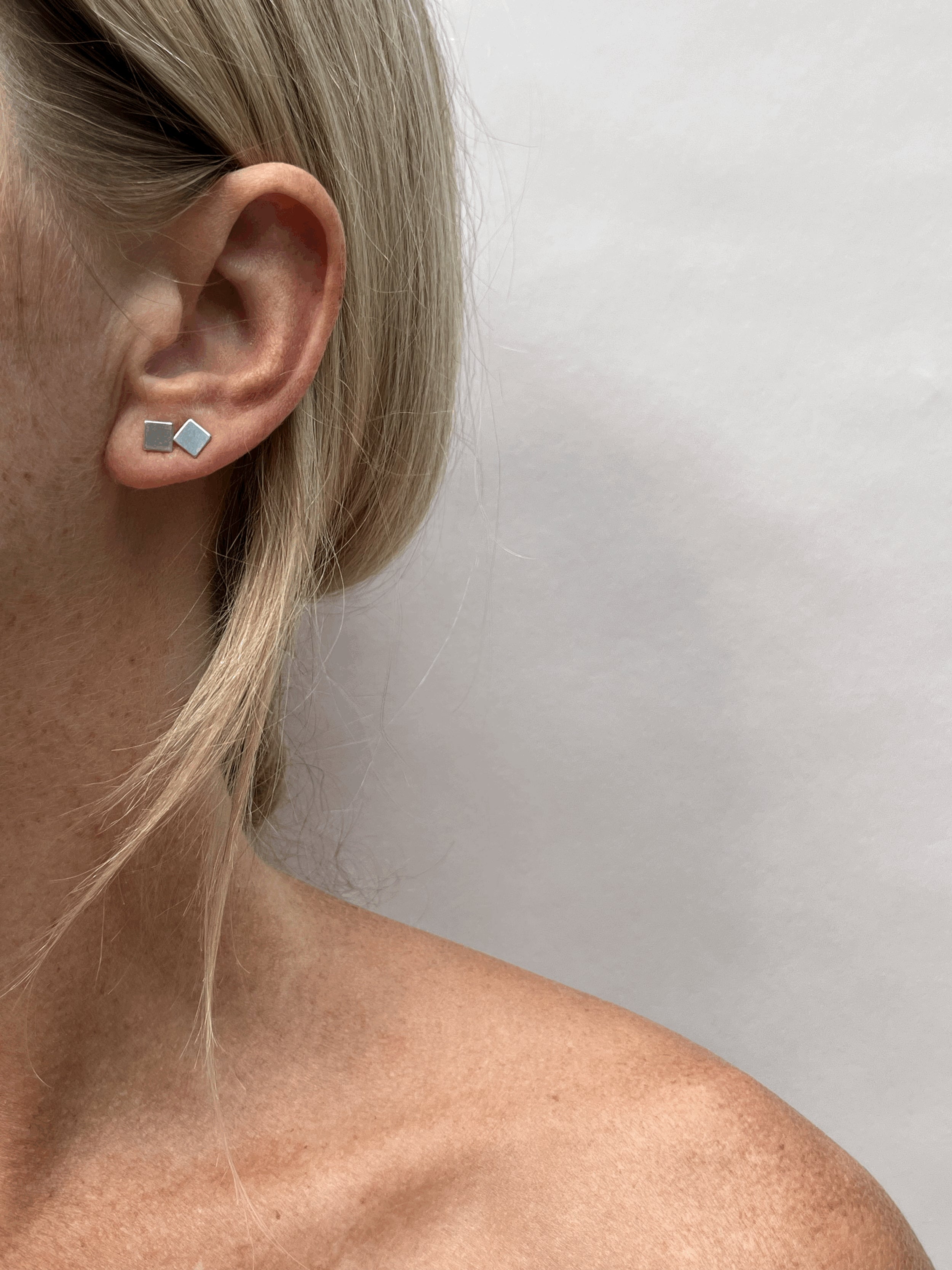 Model wearing a sterling silver square stud in the first and second ear piercing