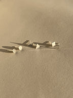 Pair of sterling silver square studs, pair of sterling silver triangle studs, and pair of sterling silver circle studs displayed on a neutral background.