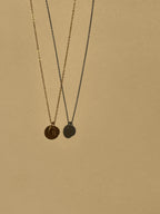 Yellow gold-filled Stamped Letter Charm Necklace with 7mm and 9mm disc charms suspended in air against a neutral background