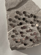 Closer view of sterling silver 7mm and 9mm disc charms with all letters of the alphabet stamped, shown grouped on a light background