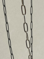 Close-up of the sterling silver medium link paperclip necklace suspended in air, chain softly blurred for an artsy effect