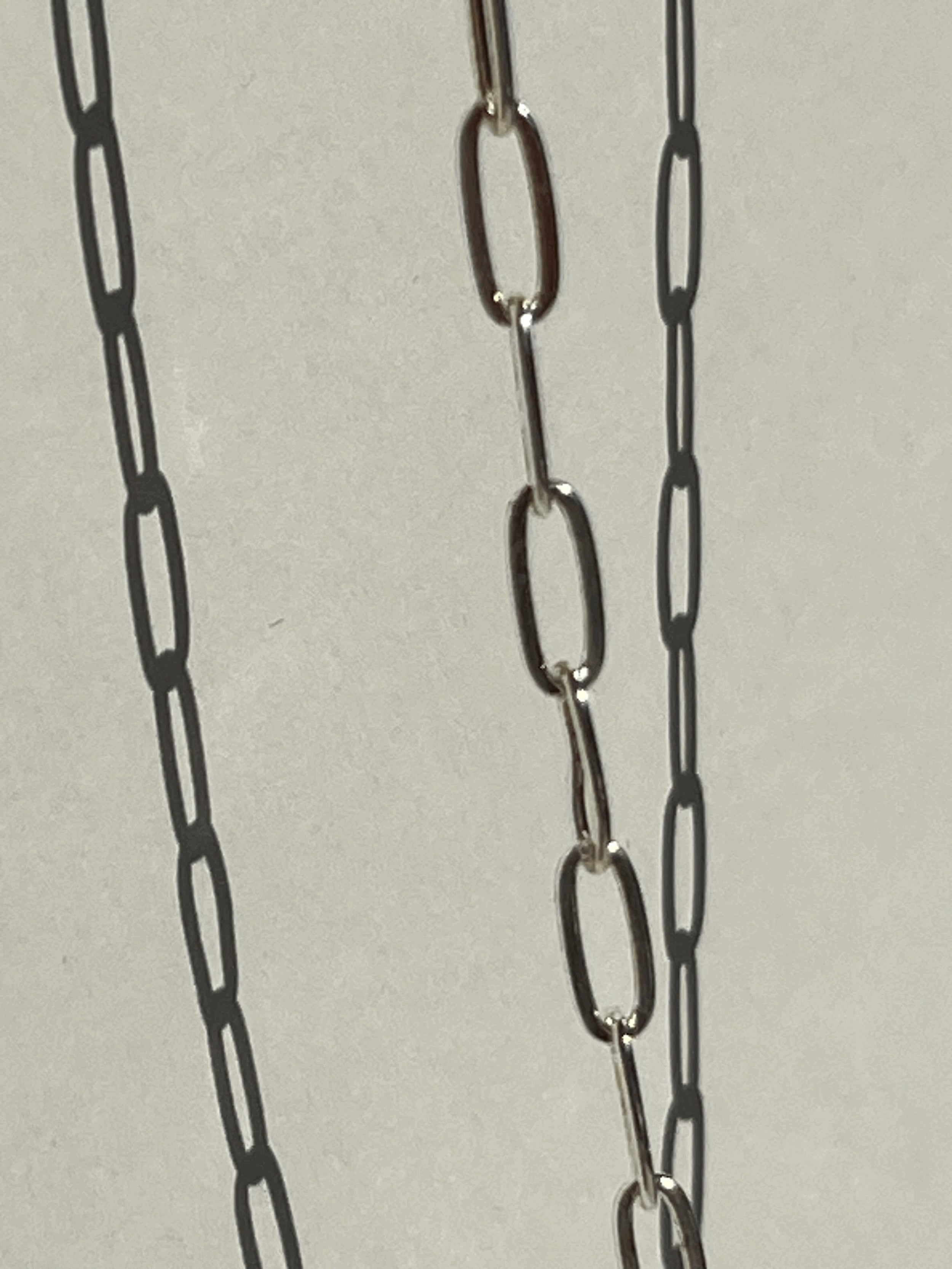 Close-up of the sterling silver medium link paperclip necklace suspended in air, chain softly blurred for an artsy effect