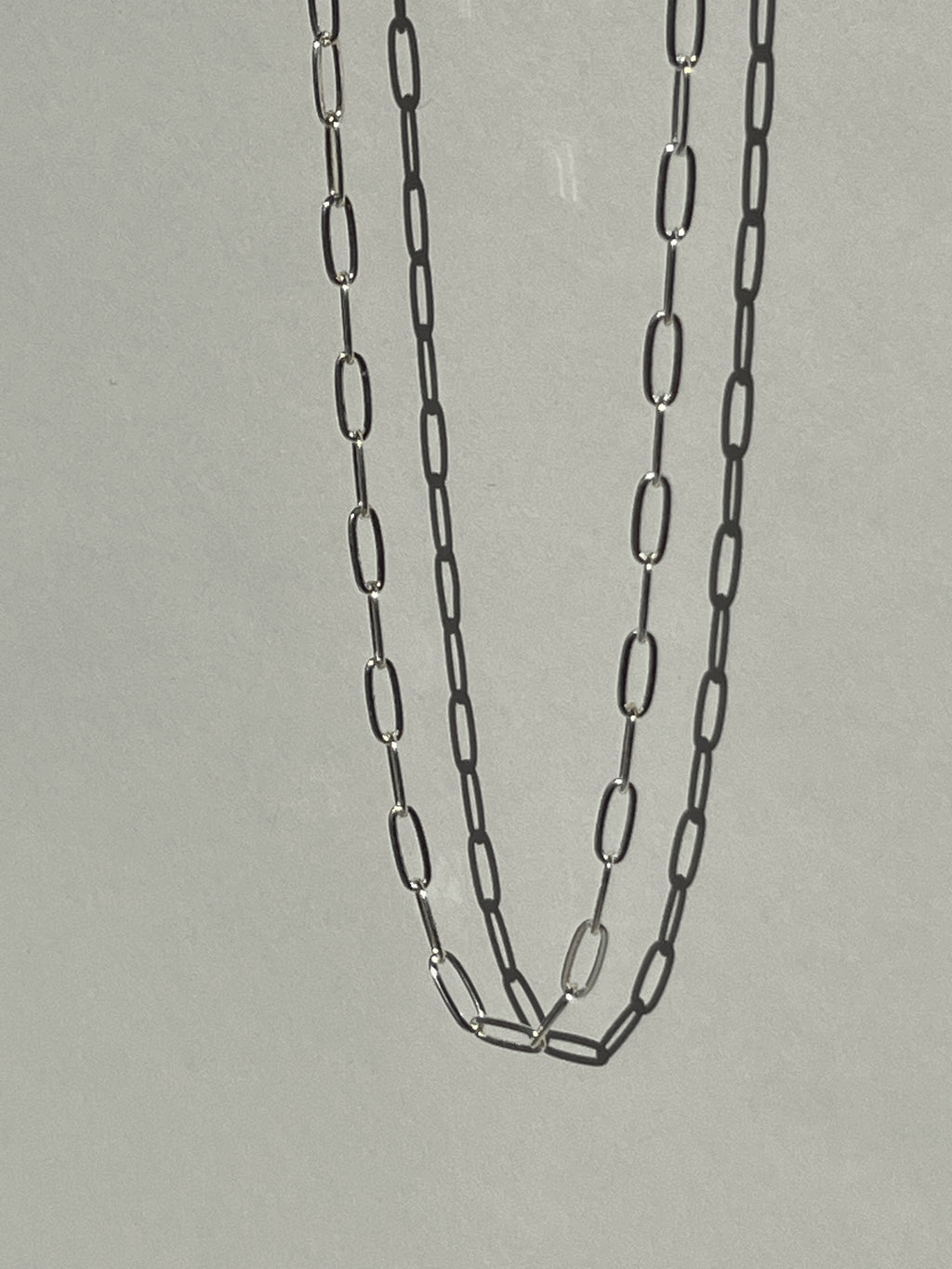 Sterling silver medium link paperclip necklace suspended in air, photographed from a different angle to show detail