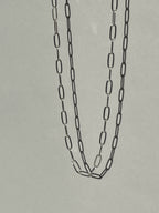 Sterling silver medium link paperclip necklace suspended in air, photographed from a different angle to show detail