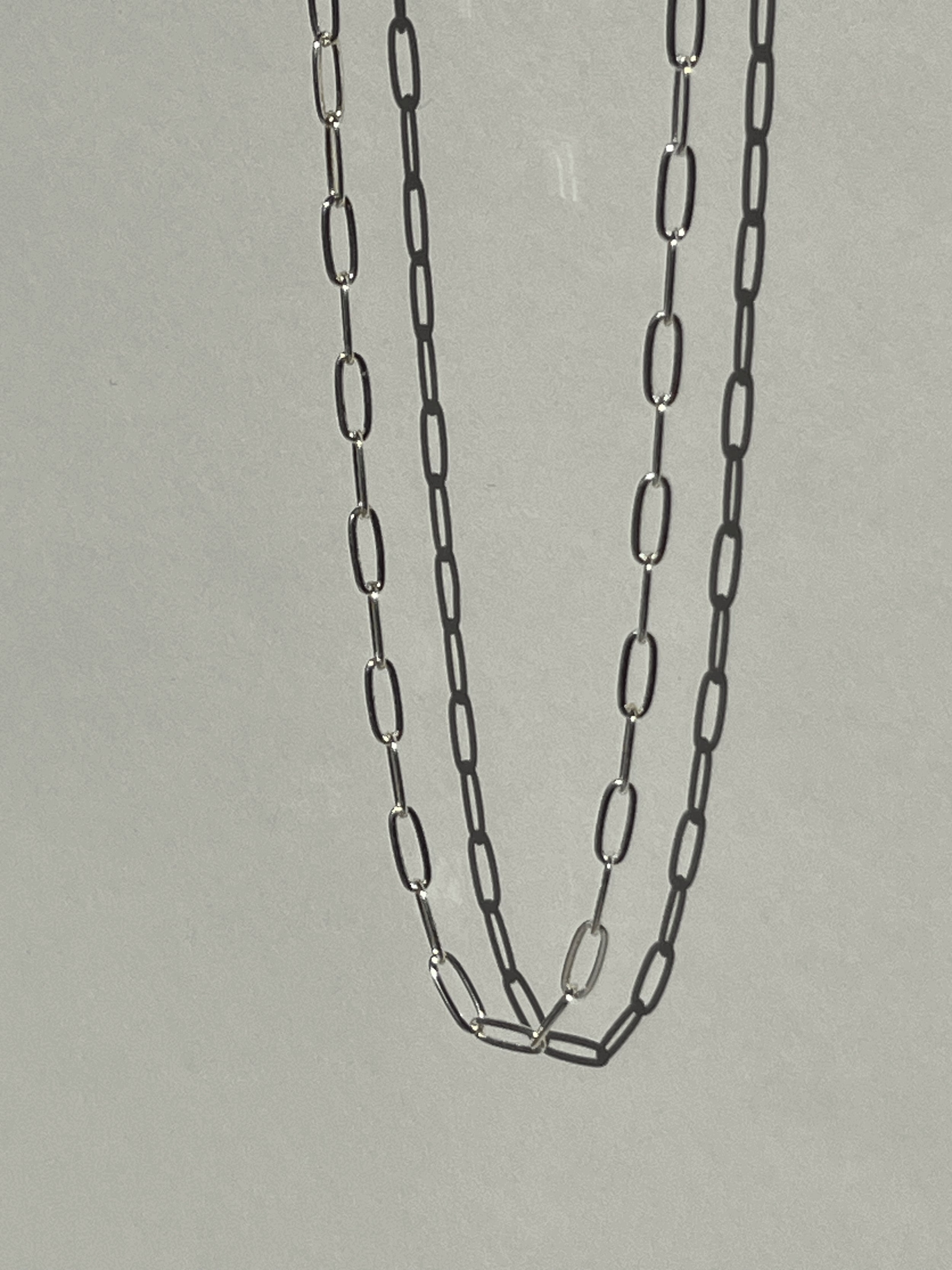 Sterling silver medium link paperclip necklace suspended in air, photographed from a different angle to show detail