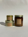 Thalken Teacher’s Pet Candle in three sizes — small gold tin, medium gold tin, and large brown glass jar — fresh and bright with notes of orchard apples, cinnamon, and a hint of citrus