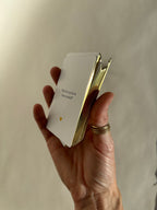 Close-up of a hand holding the Thalken Heart Questions deck, highlighting the shimmering gold-gilded edges