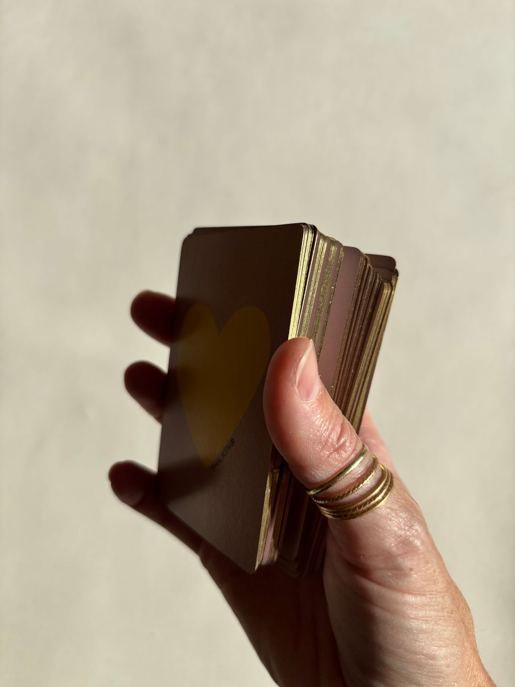 Angled view of Thalken Heart Questions Volume 2 cards highlighting the shimmering gold-gilded edges