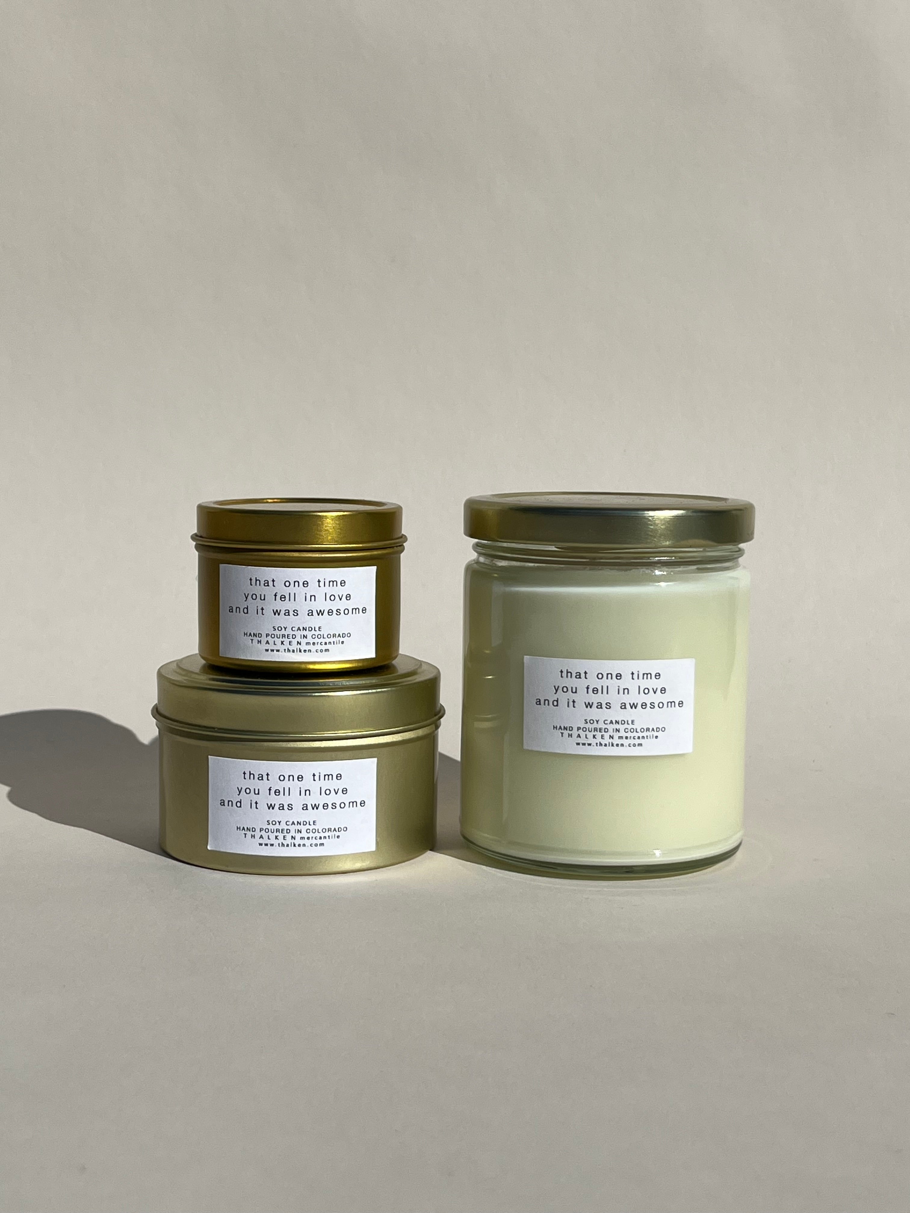 Thalken® ‘That One Time You Fell in Love and It Was Awesome’ candles in three sizes — 2oz and 6oz gold tins and 8oz soft-glow glass jar. Scent profile: floral lavender, citrus blossoms, and a hint of white musk