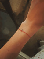 Close-up of the Thalken I AM bracelet on a slender wrist, emphasizing the bracelet’s delicate, dainty red cord and design 