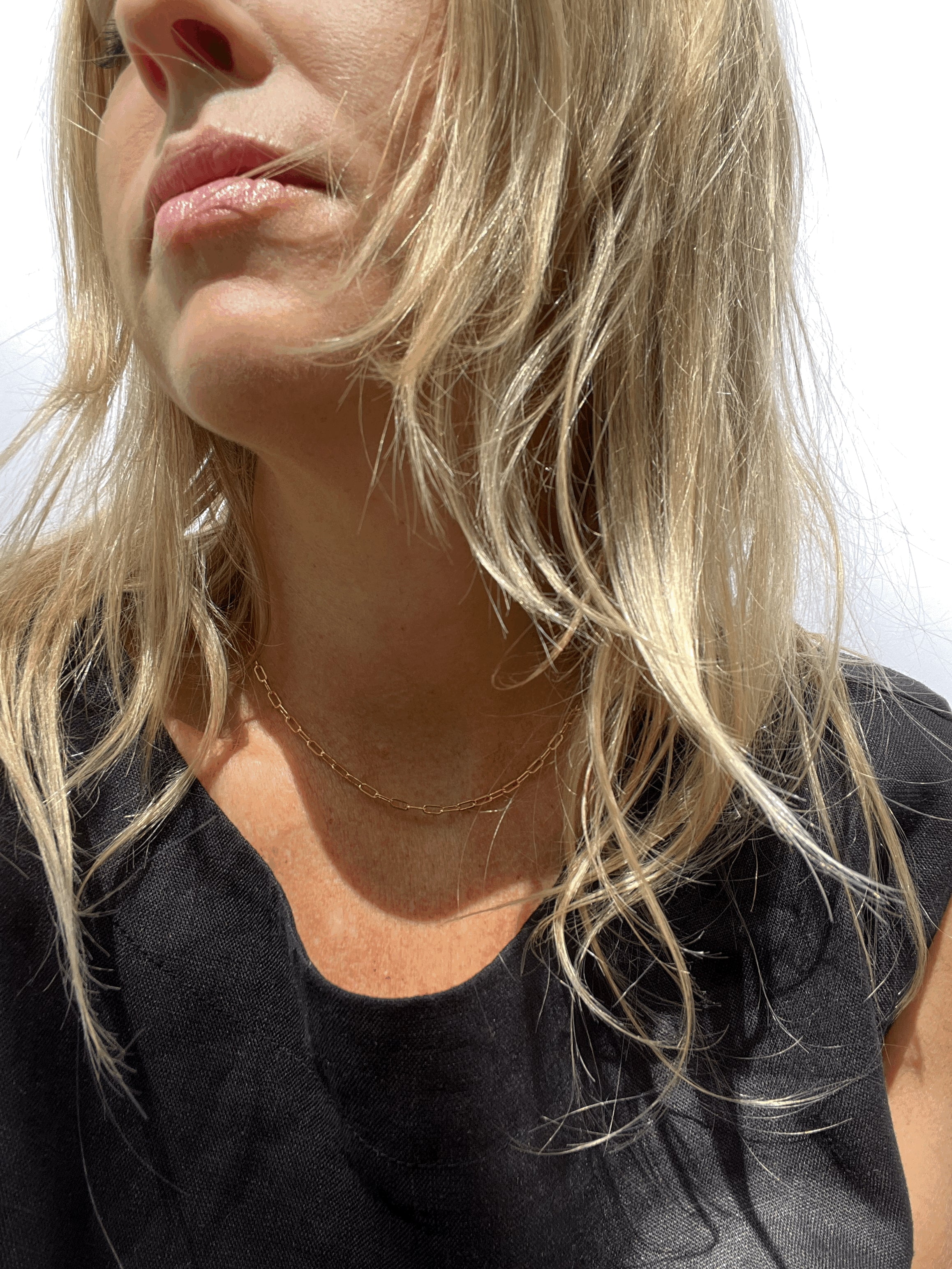 Model with blond hair wearing the rose gold-filled small link paperclip necklace with a black linen top