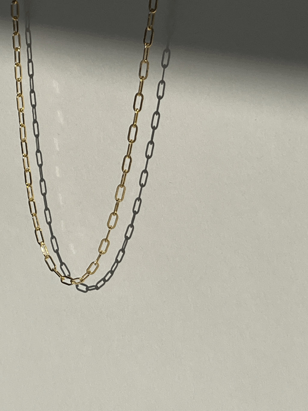 Yellow gold-filled small link paperclip necklace suspended in air with soft shadows