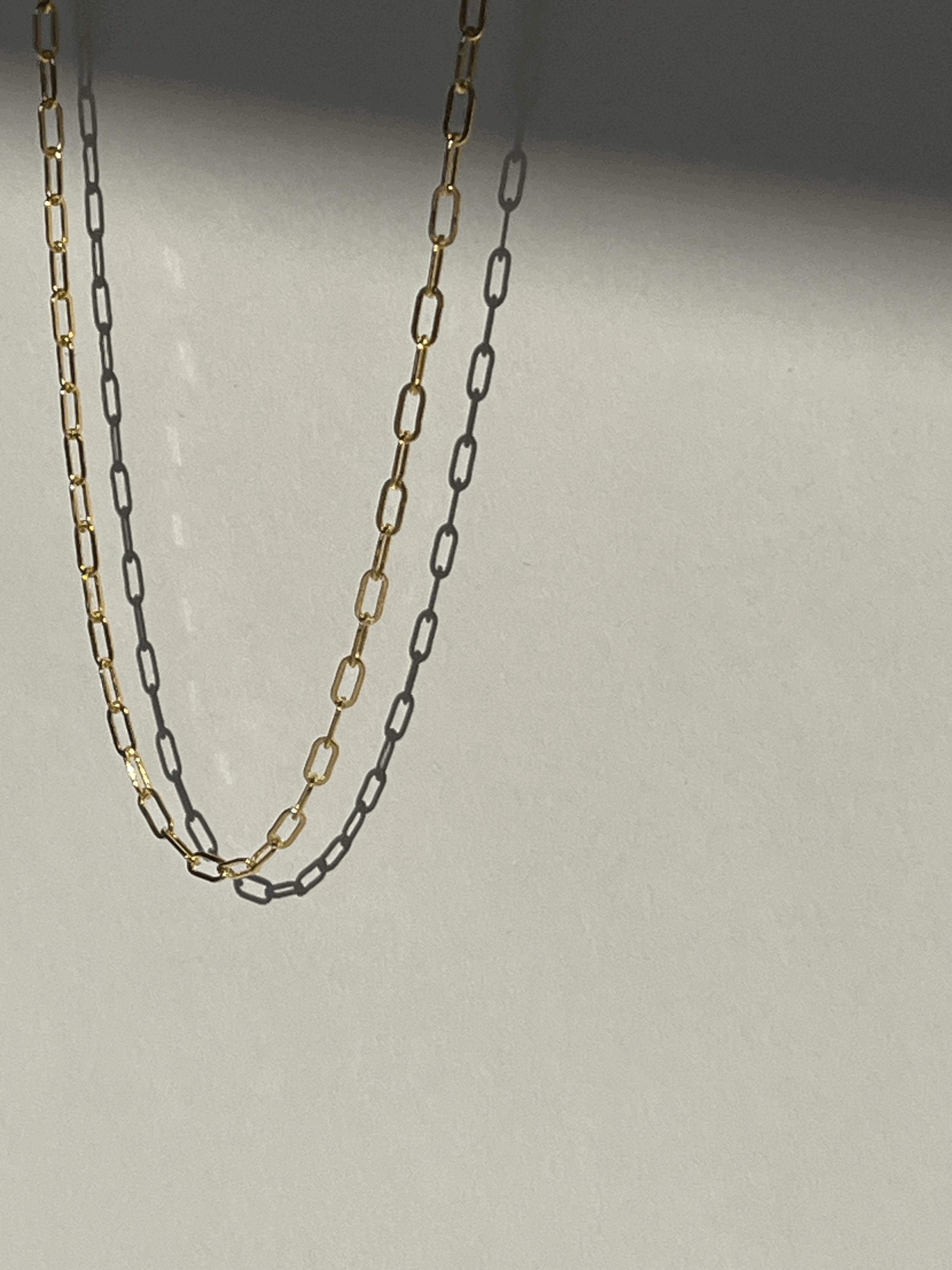 Yellow gold-filled small link paperclip necklace suspended in air with soft shadows