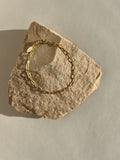 Thalken’s Small Link Paperclip Bracelet in yellow gold-filled resting on a rock, glowing in warm natural light