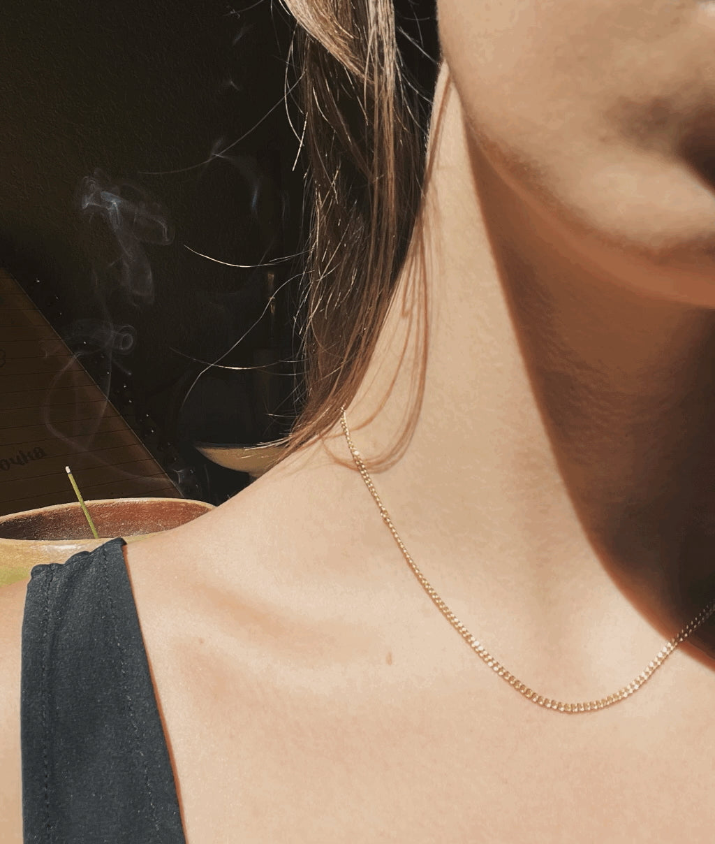 Model wearing Thalken's Perfect Yellow Gold-Filled Curb Chain Necklace, artistic shadows emphasize the minimalist design