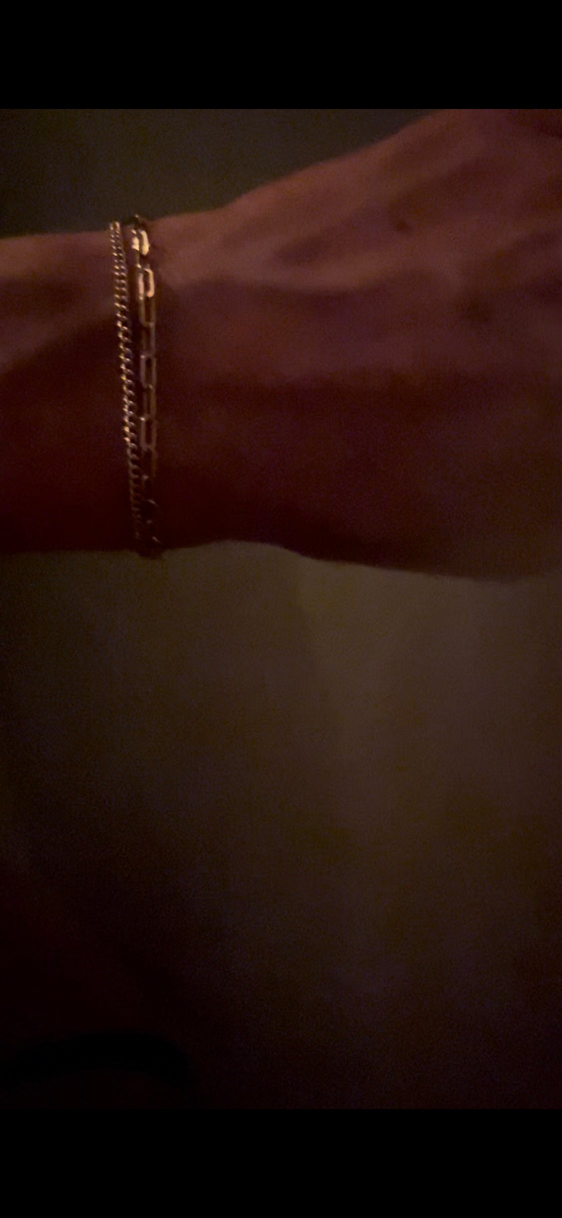 Thalken’s Small Link Paperclip Bracelet stacked with The Perfect Curb Chain Bracelet, worn on a wrist in a dark, romantic setting