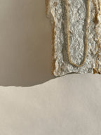 Necklace displayed on a natural organic rock, highlighting the warm glow of the yellow gold-filled chain