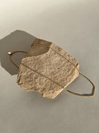 Necklace styled over rock in a different arrangement, captured in warm natural light with soft highlights