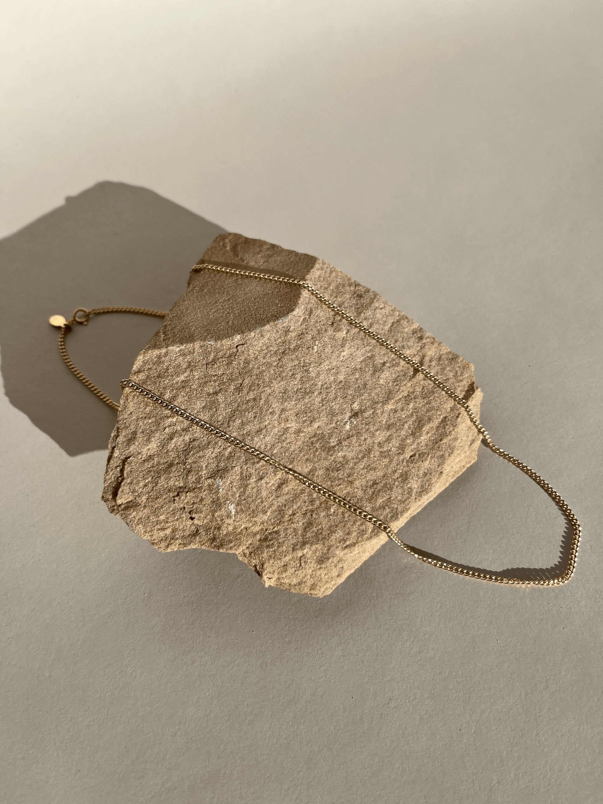 Necklace styled over rock in a different arrangement, captured in warm natural light with soft highlights