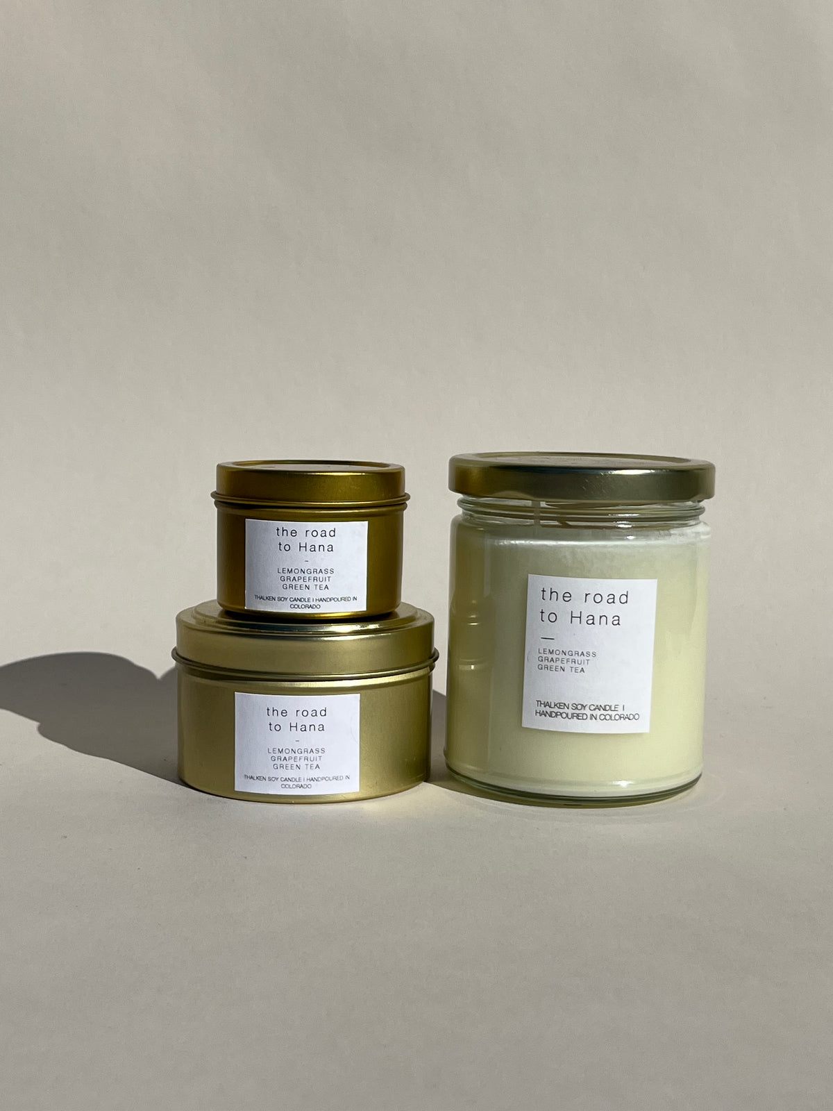 Thalken® Road to Hana candles in three sizes — 2oz and 6oz gold tins and 8oz soft-glow glass jar. Scent profile: fresh and crisp with notes of green tea, grapefruit, and lemongrass