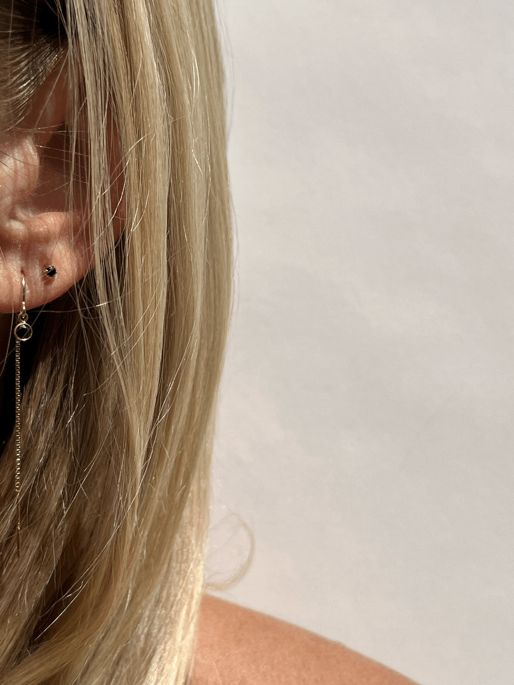 Model wearing Thalken’s yellow gold-filled black cubic zirconia bezel threader earring in her first ear piercing, paired with black Itty Bitty Crystal Studs in her second piercing, available in a separate listing