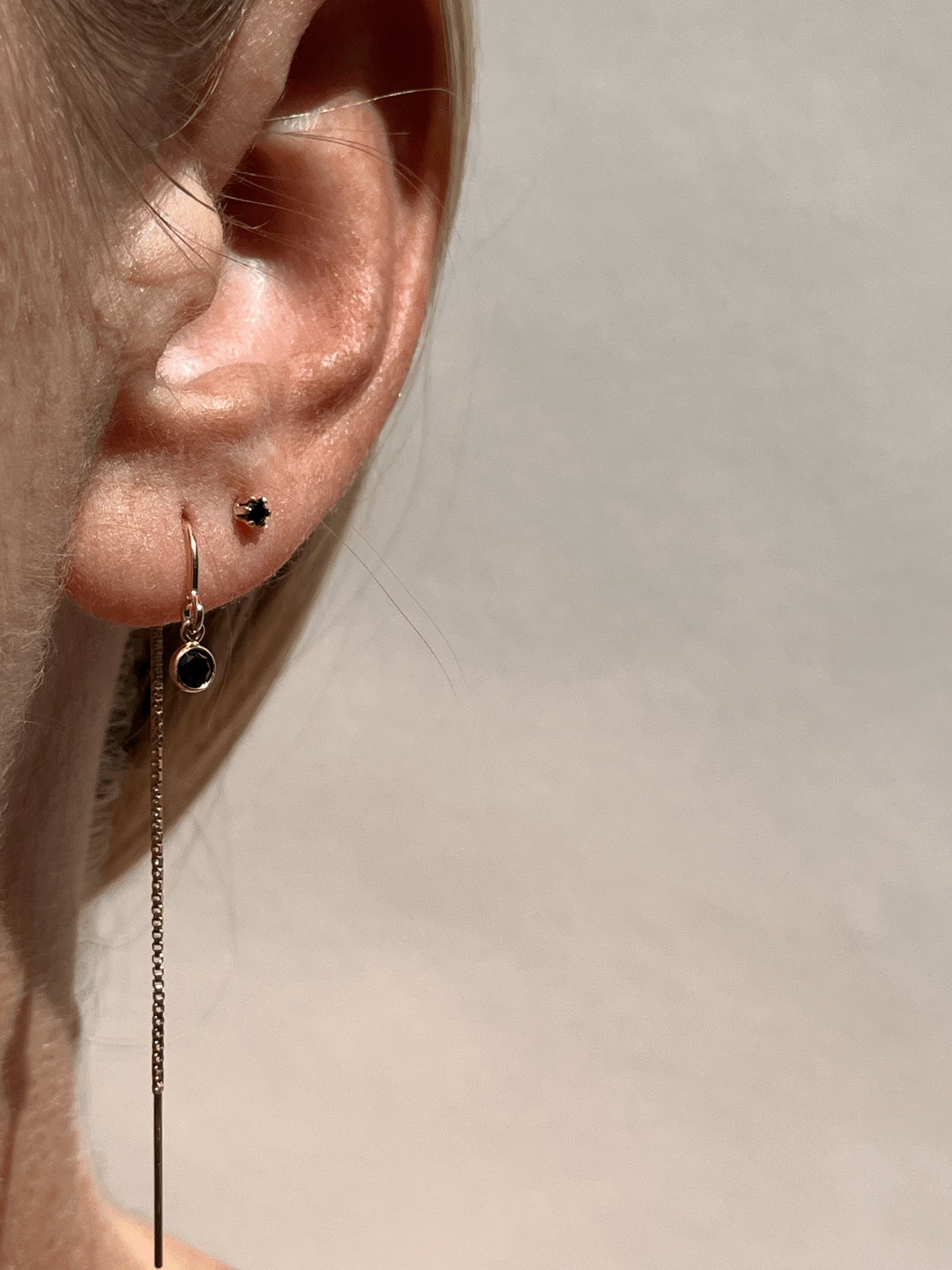 Close-up of model wearing Thalken’s yellow gold-filled black cubic zirconia bezel threader earring and matching black Itty Bitty Crystal Studs, sold separately