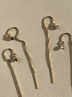 Flat-lay of Thalken’s yellow gold-filled CZ bezel threader earrings with clear and black cubic zirconia, styled for a minimalist aesthetic