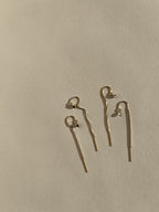 Distant product shot of Thalken’s yellow gold-filled CZ bezel threader earrings on a neutral background, showing both clear and black cubic zirconia options