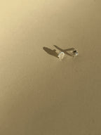 Pair of tiny sterling silver shell stud earrings on a neutral background