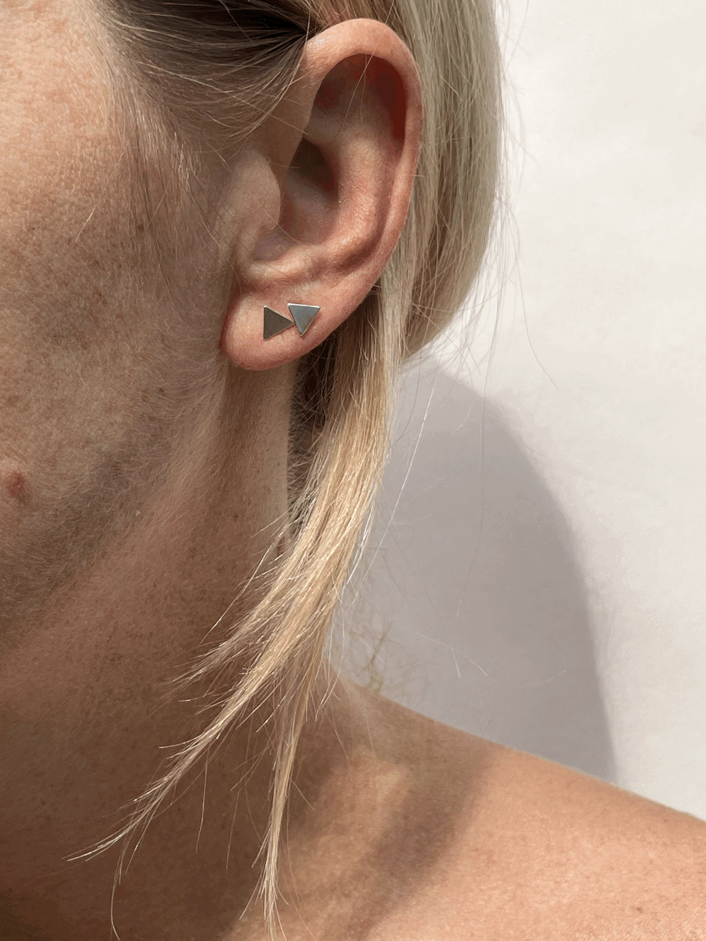 Model wearing a sterling silver triangle stud in the first and second ear piercing