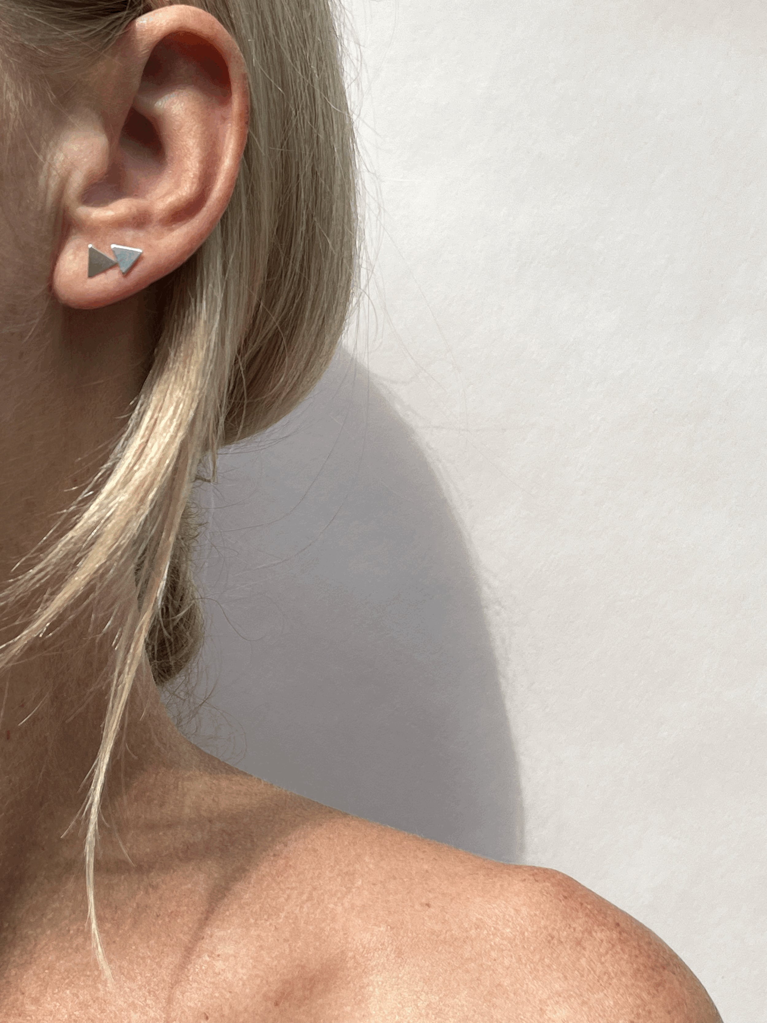 Model wearing a sterling silver triangle stud in the first and second ear piercing