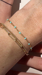 Close-up of model’s wrist wearing Thalken® bracelet stack with turquoise enamel bead bracelet, other hand resting behind wrist