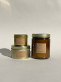Three Thalken Vegas candles in small and medium gold tins and a large brown glass jar