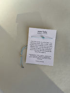 Water Baby light-blue cord bracelet with natural aquamarine displayed on printed bracelet card
