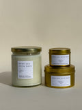 Photo of Thalken’s When You Smile Back candle shown in three vessel options — sleek gold tins (2oz and 6oz) and a soft-glow glass jar (8oz). Bright and sunny scent profile with notes of pineapple, oakmoss, and sage.