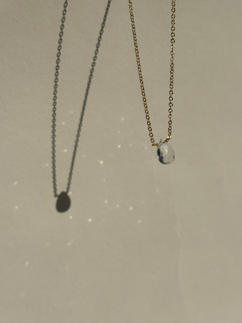 Thalken Natural White Topaz Drop Necklace suspended in air with sparkling light reflections from the stone