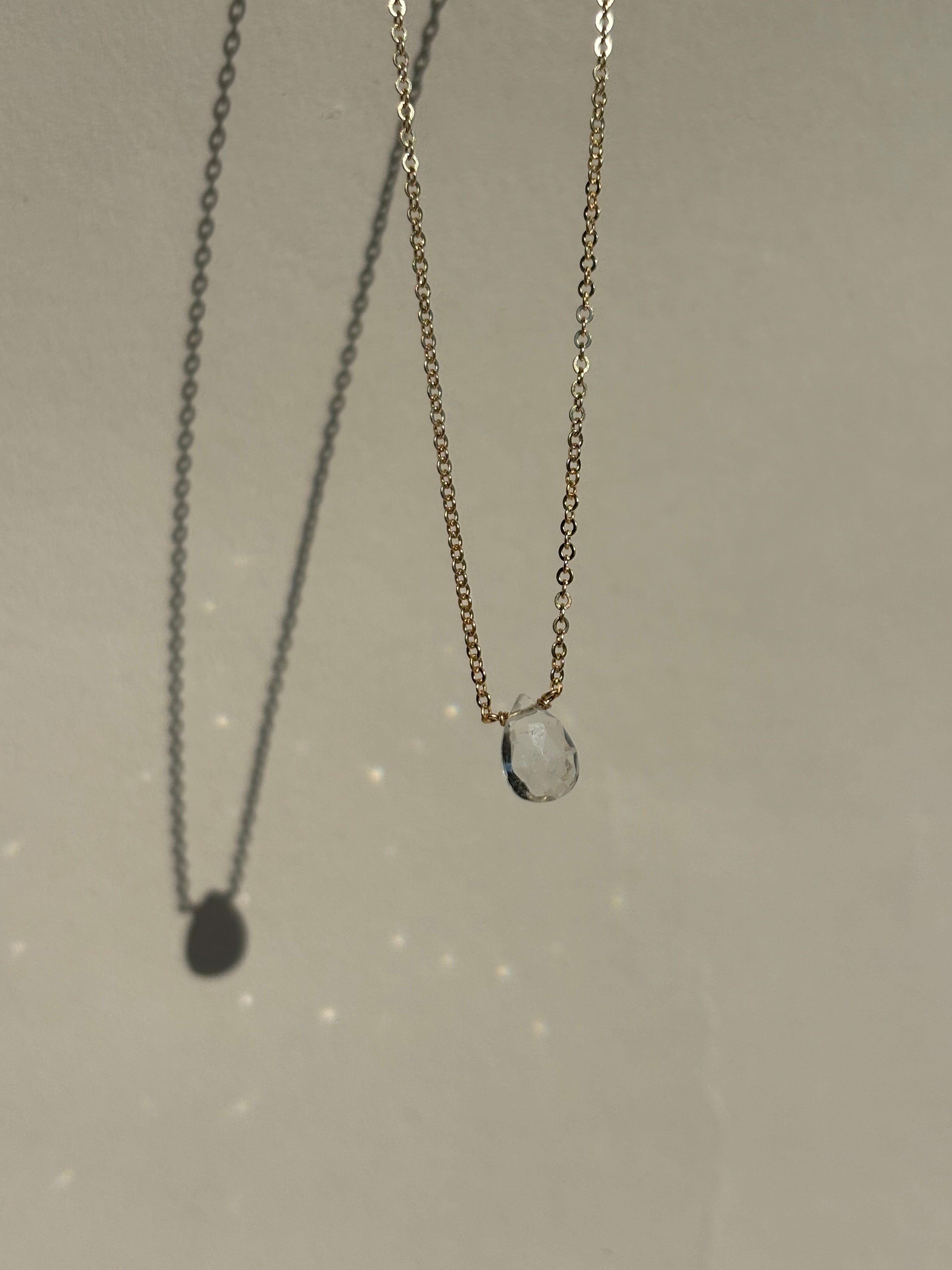 Thalken Natural White Topaz Drop Necklace suspended in air with sparkling light reflections from the stone