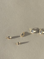 Assortment of Thalken 14k gold single drop earring charms in white topaz, displayed in pear, oval, and marquise shapes, unattached to hoops for customizable styling