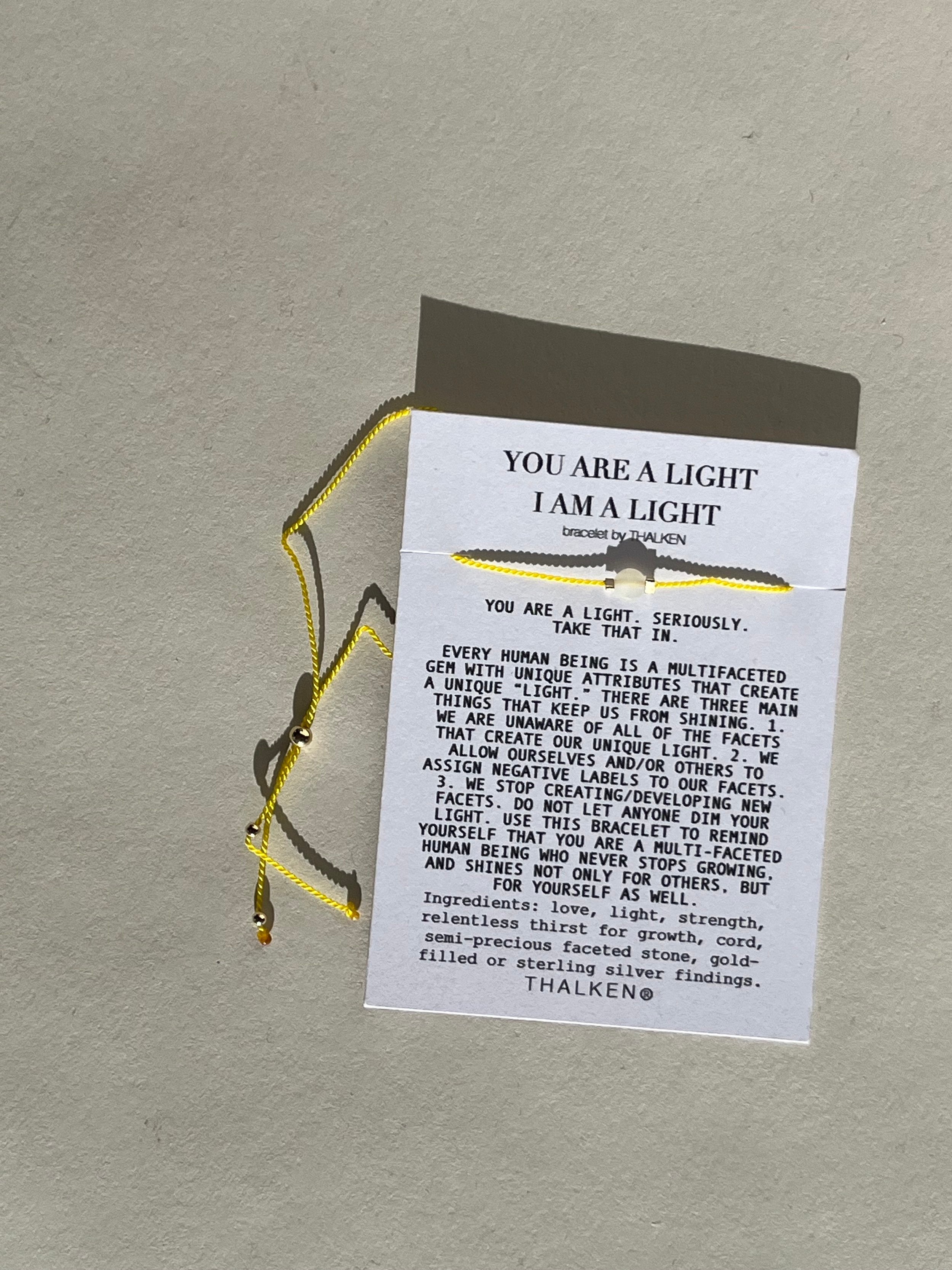 Thalken® ‘You Are a Light’ mantra bracelet displayed on a paper card showing the full mantra text